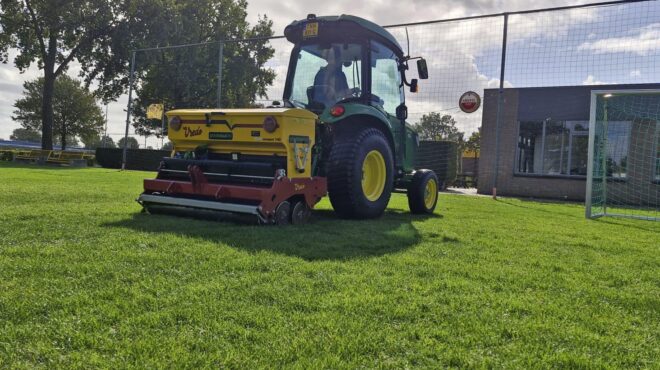 WhatsApp Image 2026-01-12 at 16.48.12 Vredo doorzaaimachine achter een compacte trekker op een voetbalveld